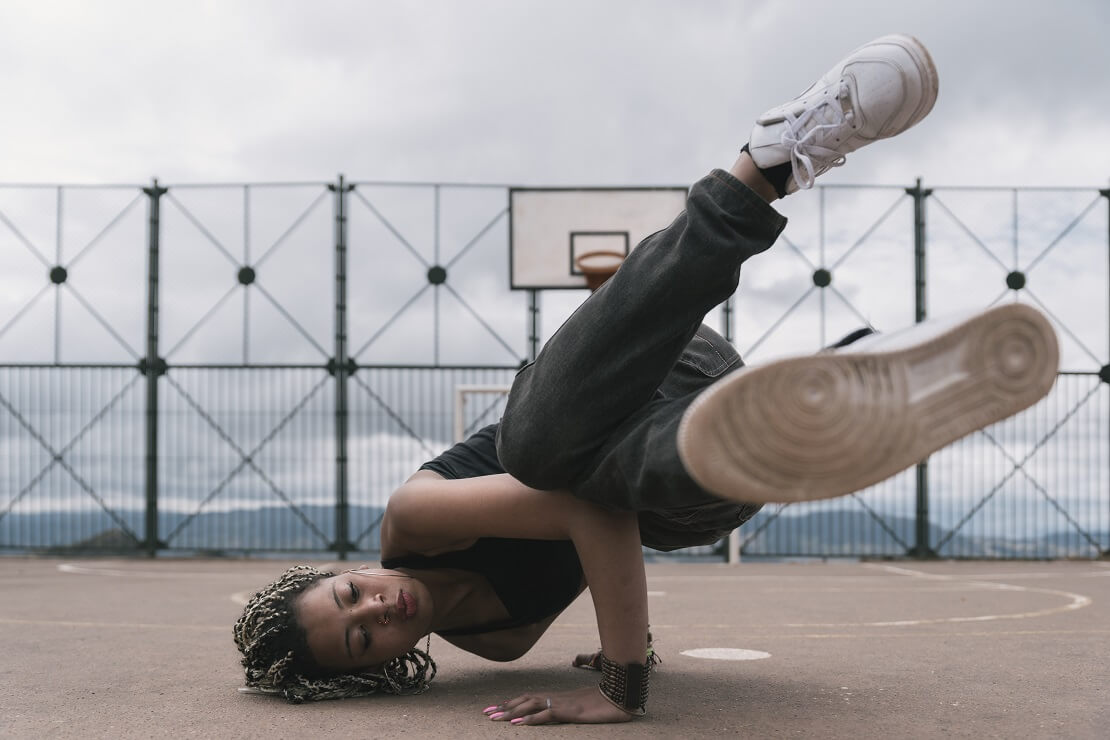 Mädchen macht Breakdance auf Basketballplatz