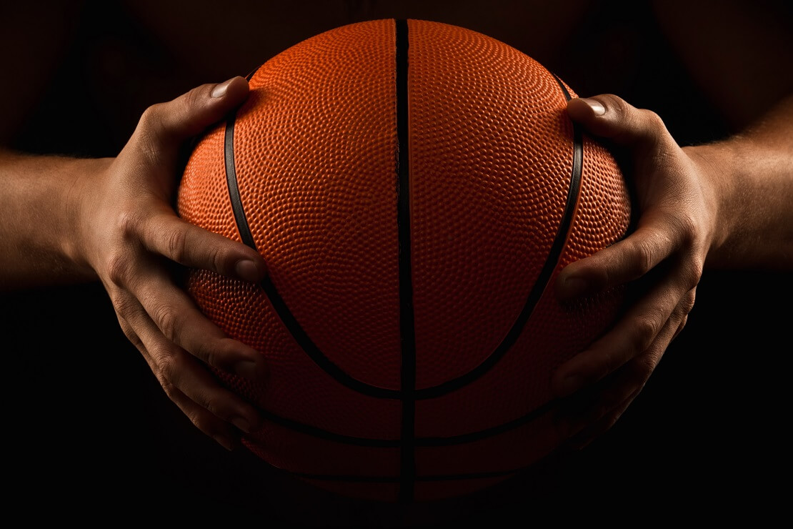 Basketballer haelt den Ball in den Haenden