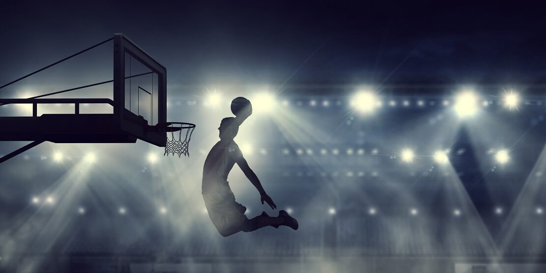 Die Silhouette eines Basketballers beim Dunking