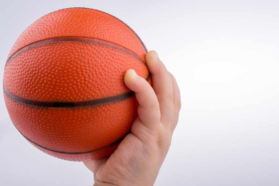 Eine Babyhand greift einen kleinen Basketball