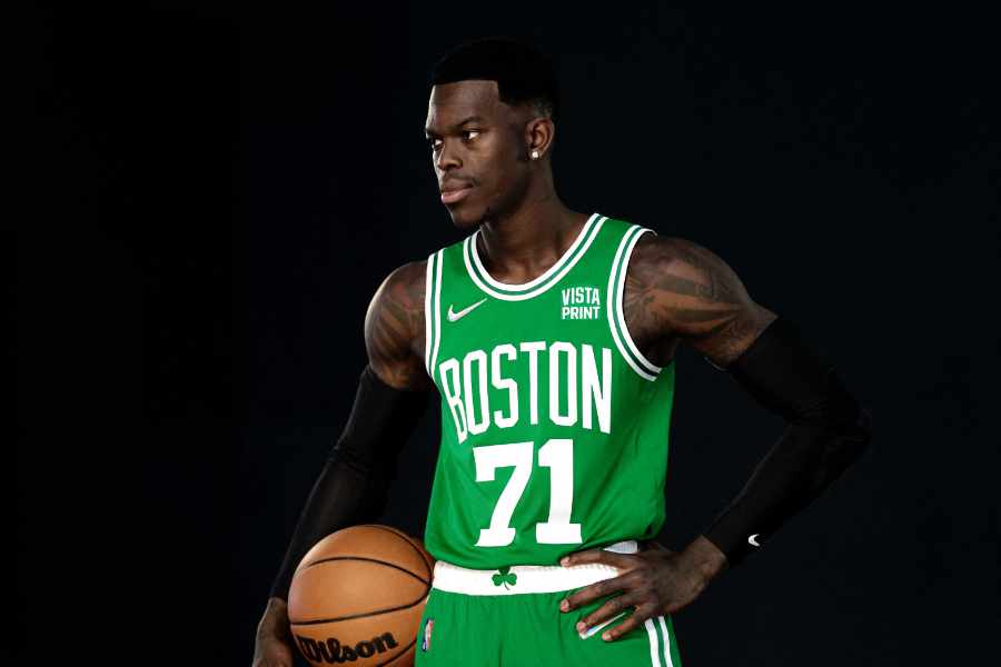 Dennis Schröder posiert im Trikot der Boston Celtics mit einem Basketball