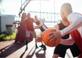 Zwei Basketballspieler kämpfen um den Ball, im Hintergrund zwei weitere Spieler