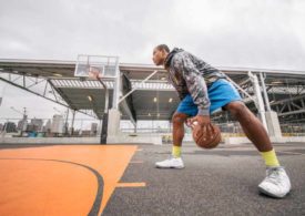 Ein Mann in Trainingsklamotten dribbelt auf einem städtischen Basketballplatz