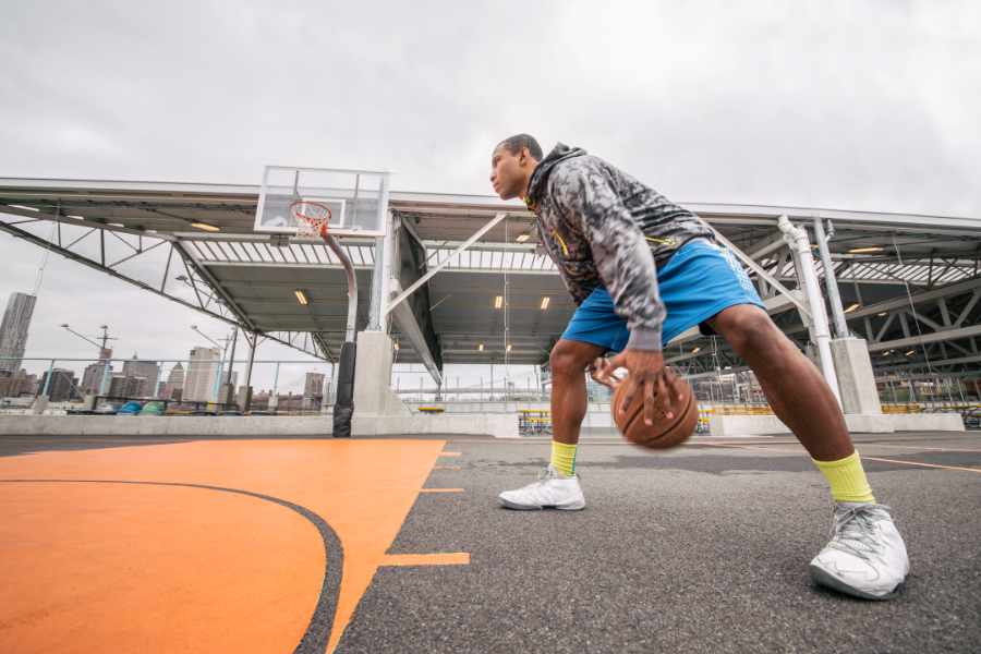 Ein Mann in Trainingsklamotten dribbelt auf einem städtischen Basketballplatz