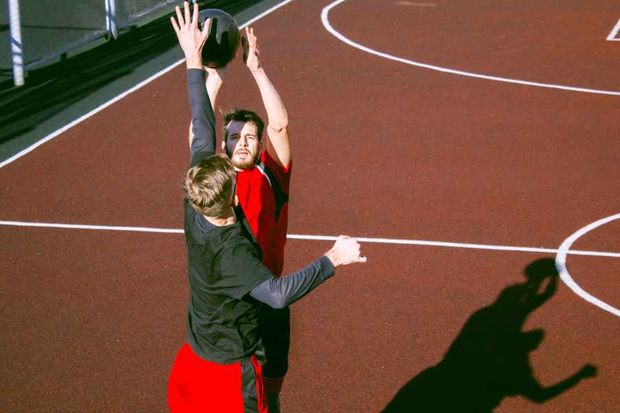 Zwei Leute spielen Basketball, einer wird vom anderen im Wurf geblockt