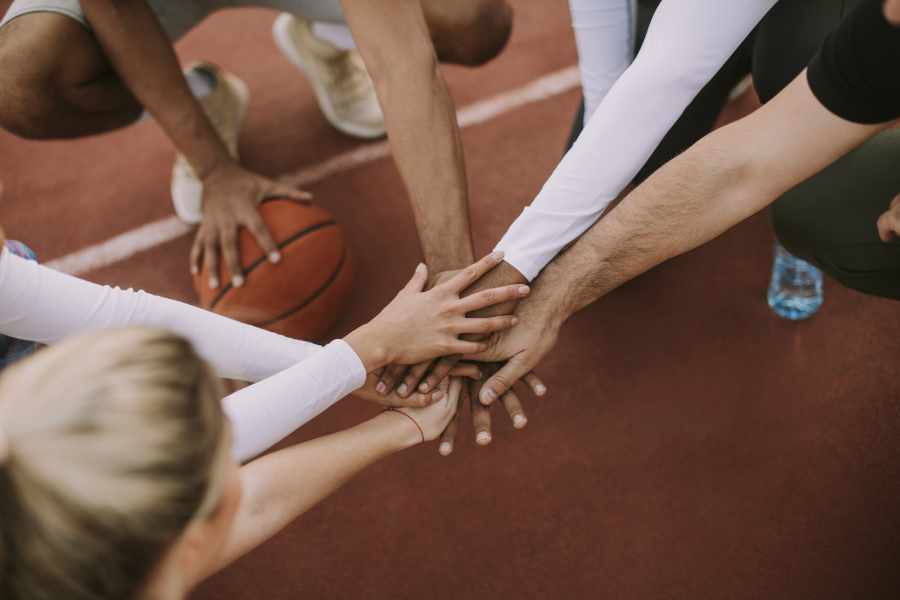 Ein Basketball Team hält ihre Hände aufeinander in die Mitte