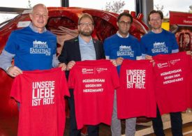 Vier Leute Stehen mit roten Tshirt in der Hand zur Kamera