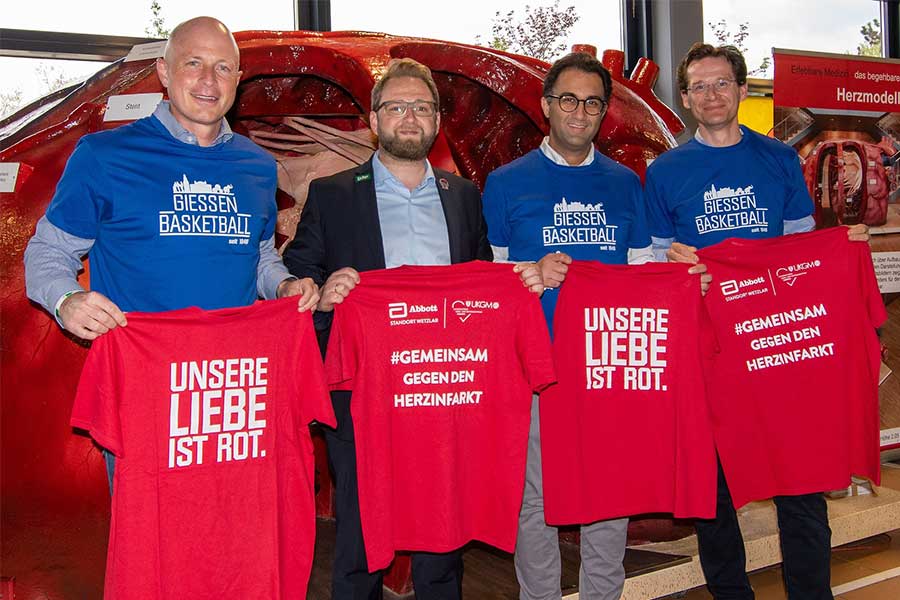 Vier Leute Stehen mit roten Tshirt in der Hand zur Kamera