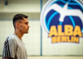 Oscar da Silva steht neben dem ALBA BERLIN Logo