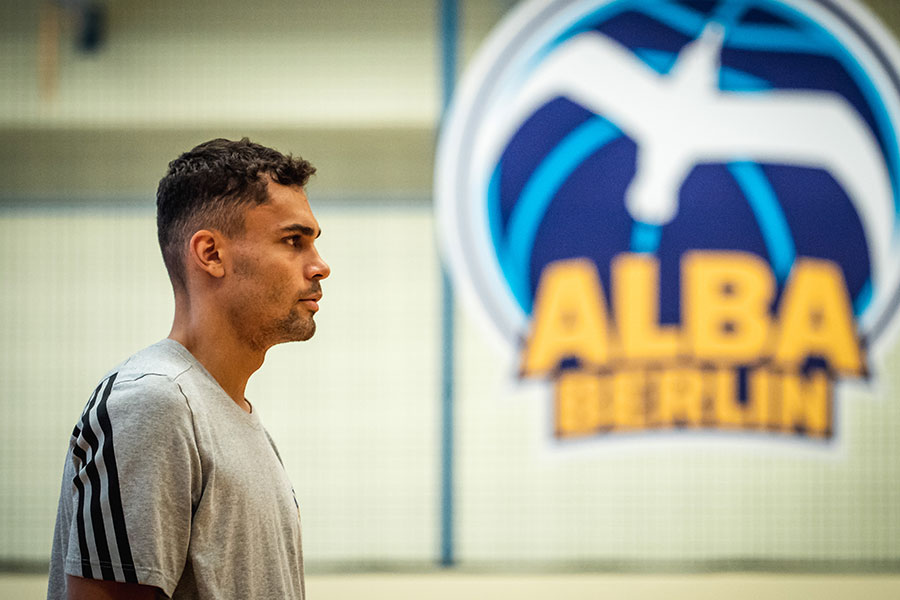 Oscar da Silva steht neben dem ALBA BERLIN Logo