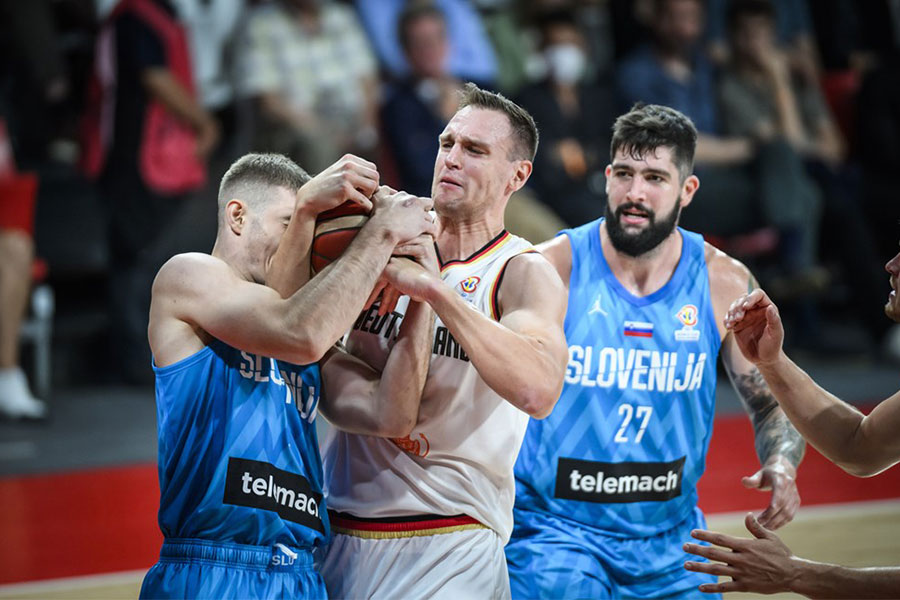 Ein deutscher Basketballspieler spielt gegen ein slowenischen Basketballspieler um den Basketball