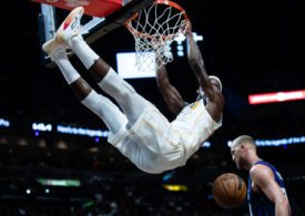 Ein Basketballspieler hängt nach dem Slamdunk am Korb