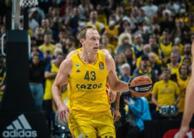 Luke Sikma hält ein Basketball in der linken Hand und im Hintergrund sieht man eine Zuschauermenge sitzen.