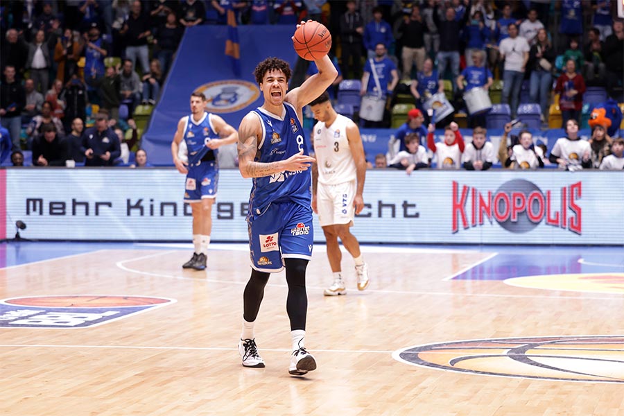 Der Basketballspieler Joshua Obiesie hält den Basketball hoch und schreit