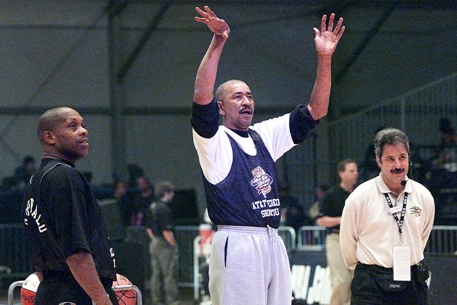 Der Basketballspieler Geroge Gervin steht wischen zwei andern Männern