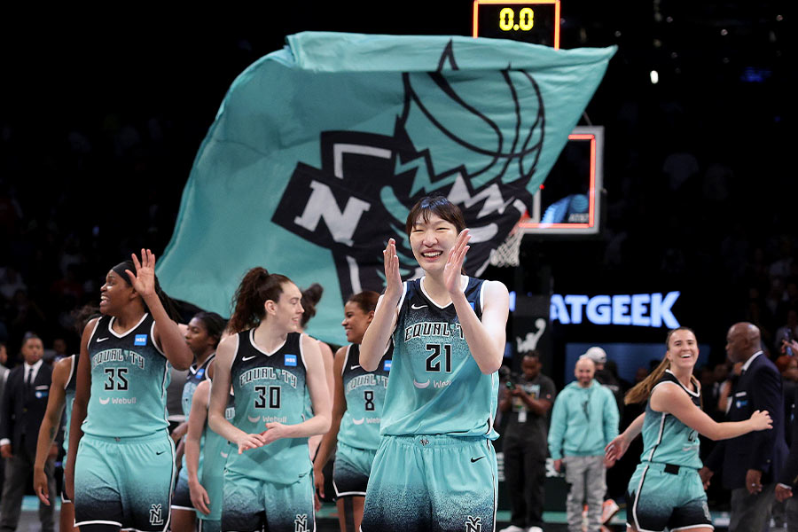 Die Basketballspielerin Han Xu von den New York Liberty steht im Vordergrund und freut sich und klatscht dabei in die Hände und im Hintergrund ist ihre Mannschaft zu sehen