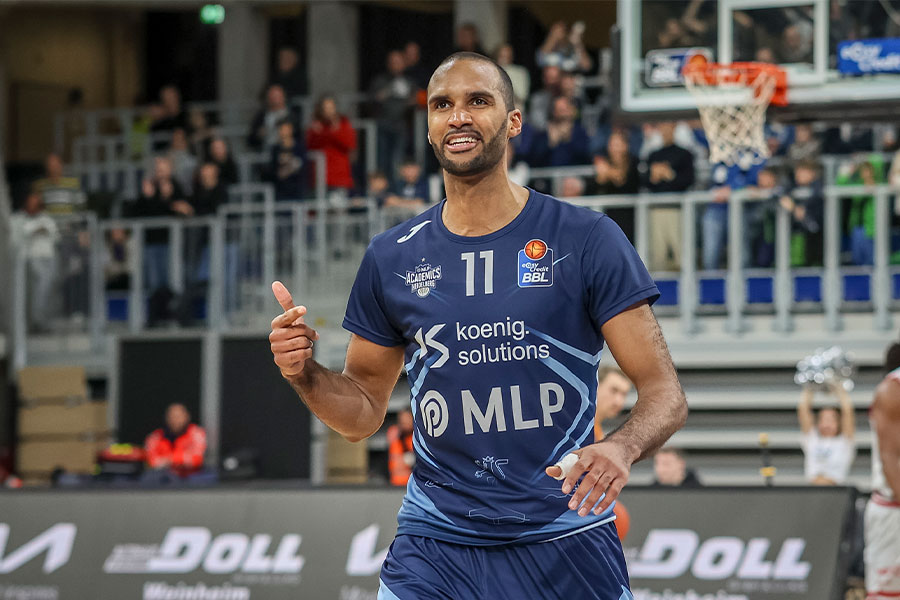 Der Basketballspieler Akeem Vargas lächelt und man sieht im Hintergrund die Tribüne mit dem Publikum