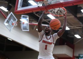 Der Basketballspieler Adrian Nelson von den Bamberg Baskets hält sich am Basketballkorb fest und schreit dabei