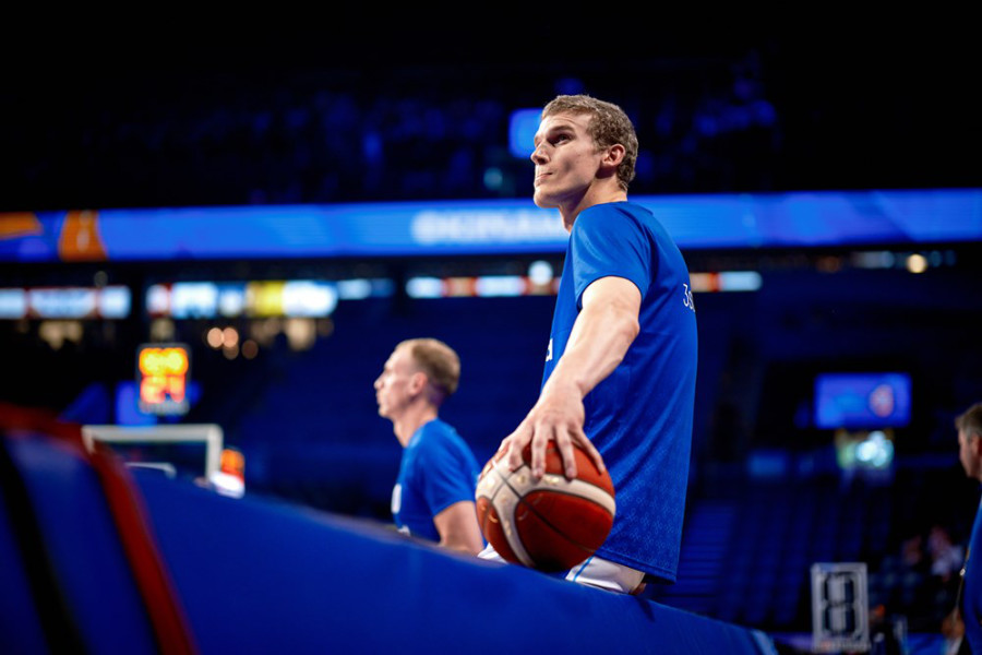 Lauri Markkanen sitzt mit Ball auf einer Bande