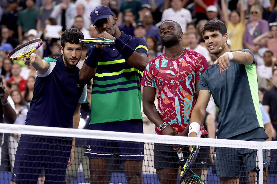 Sebastian Yatra, Jimmy Butler, Frances Tiafoe und Carlos Alcaraz posieren hinter einem Tennisnetz