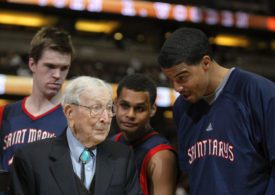 Basketball Coach John Wooden steht zwischen Spielern eines College-Teams