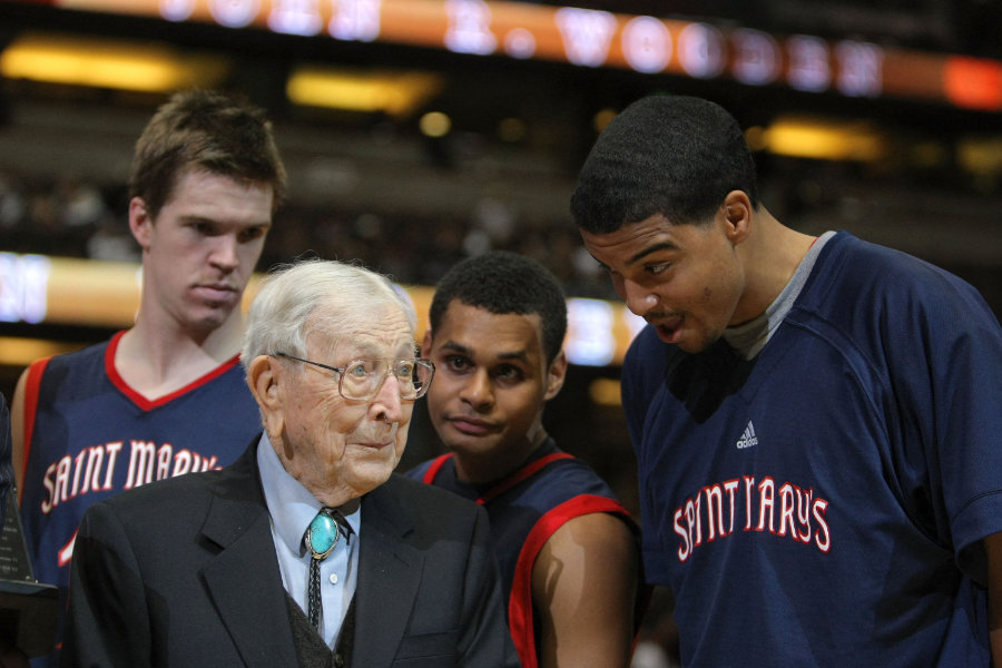 Basketball Coach John Wooden steht zwischen Spielern eines College-Teams